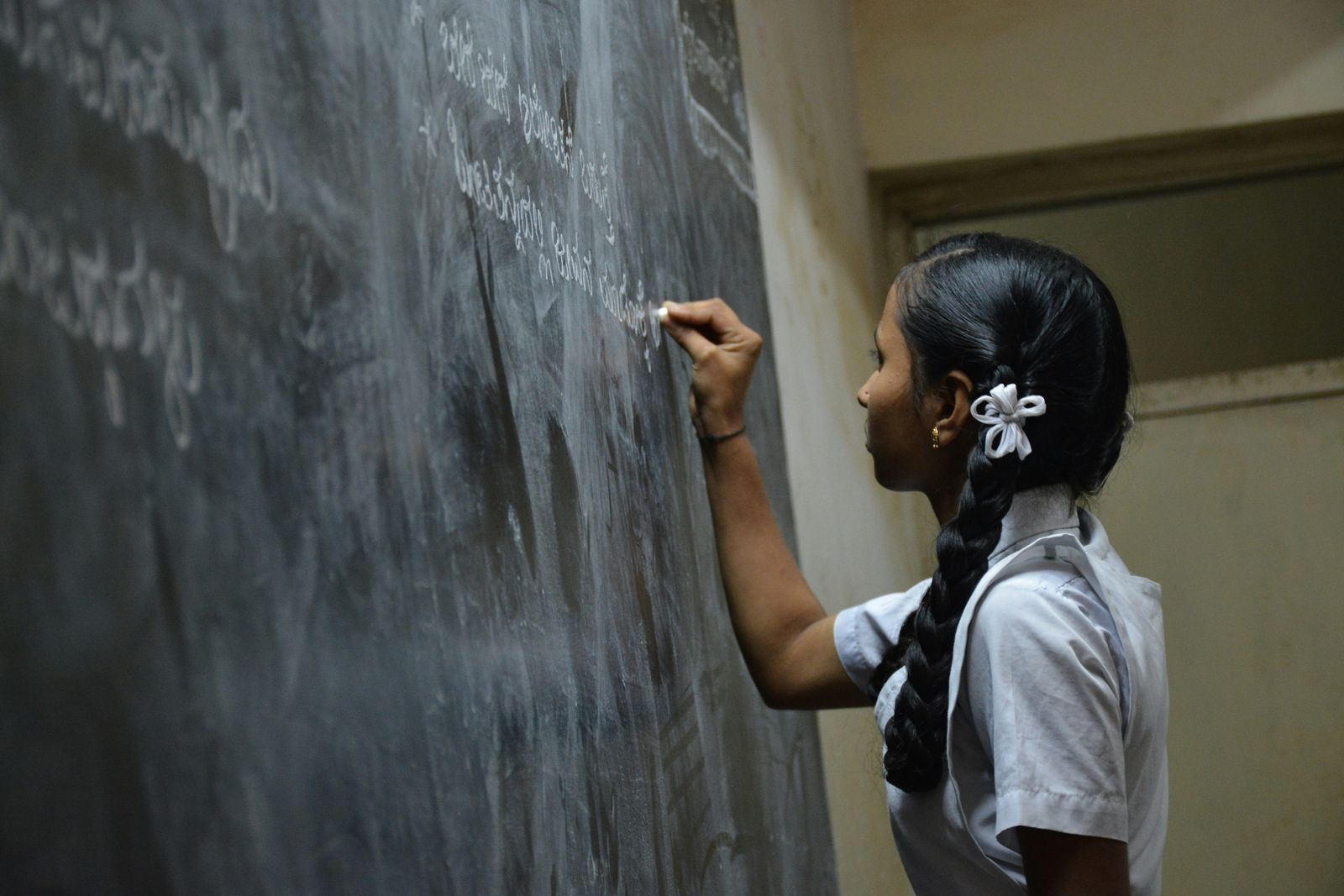 Student writing on a classroom blackboard